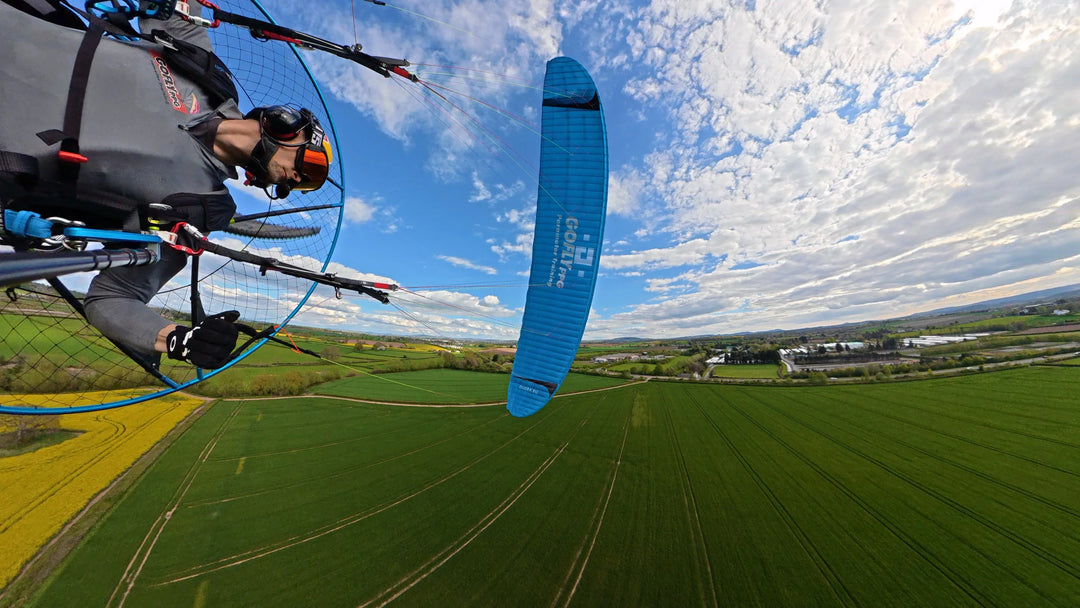 Paramotoring pilot flying over fields with custom printed paraglider vinyl graphics, UK made.
