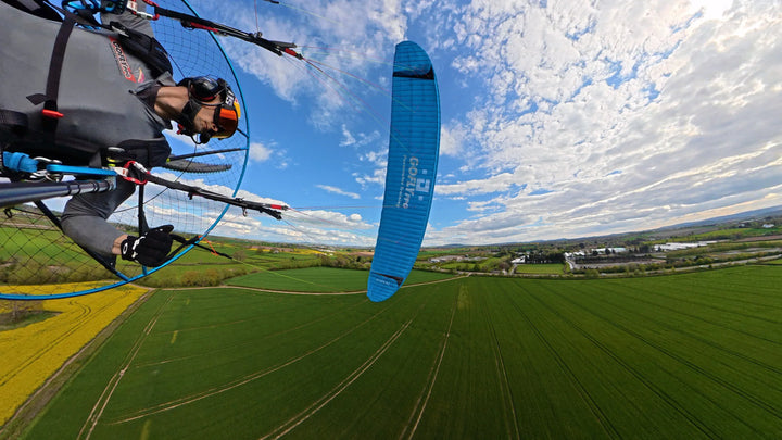 Paramotoring pilot flying over fields with custom printed paraglider vinyl graphics, UK made.